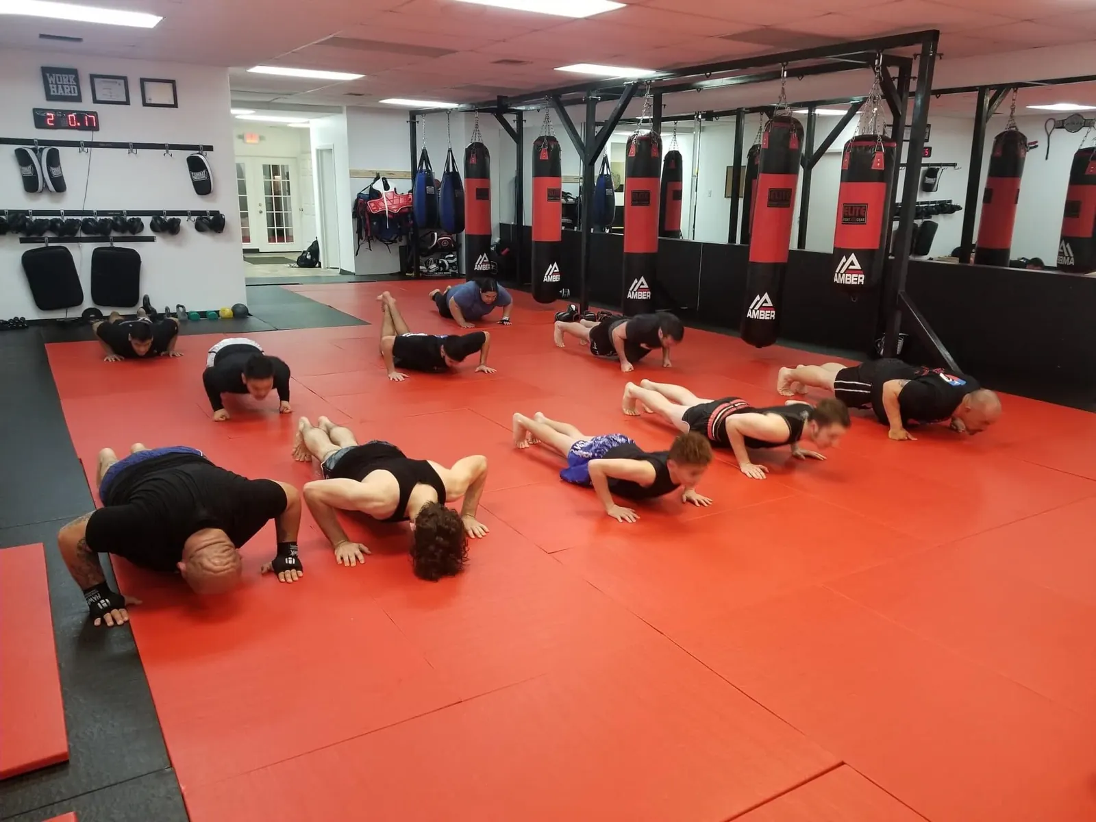 An adult Muay Thai class doing push-ups on the red mats
