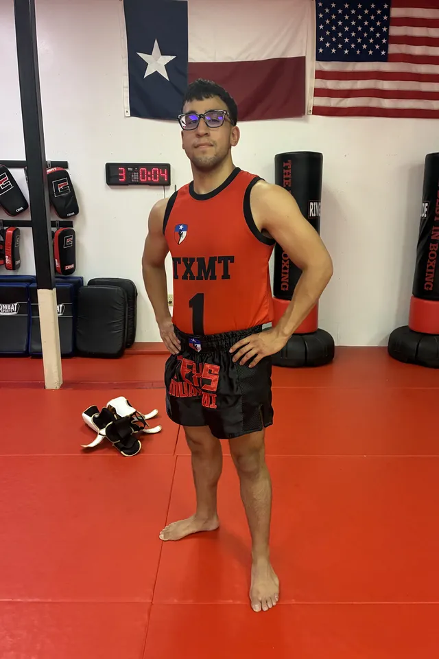 Coach Angel Razo on the mats in a red TXMT tank