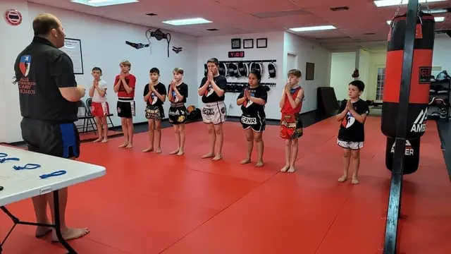 Kru Jonathan coaching a line of kids in their Muay Thai shorts