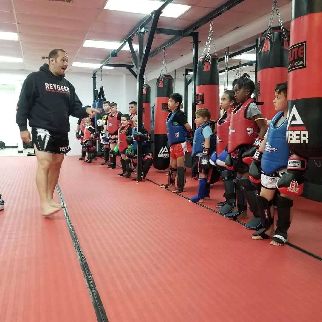 Kru Jonathan walking the line of kids in protective gear before drills