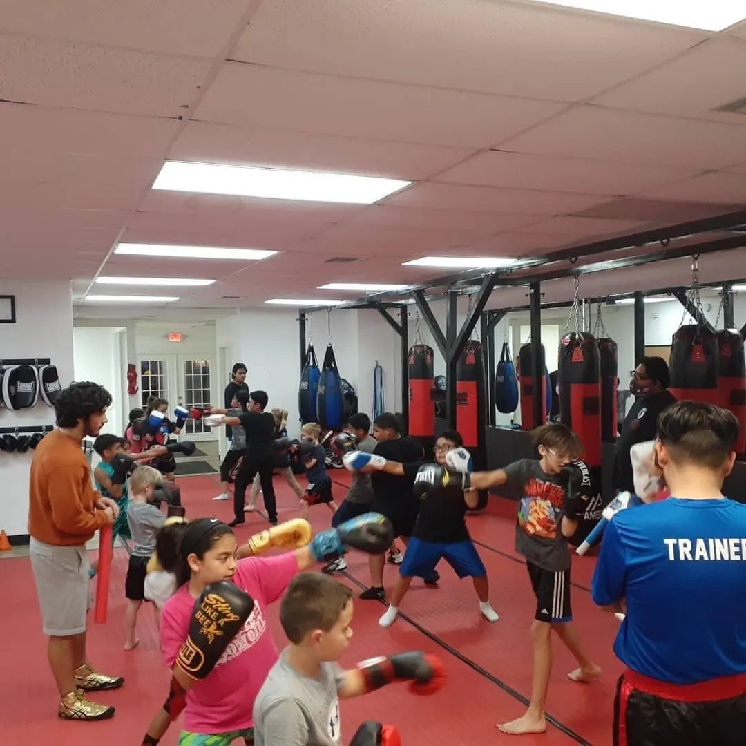 Kids practicing punches on pads with a coach