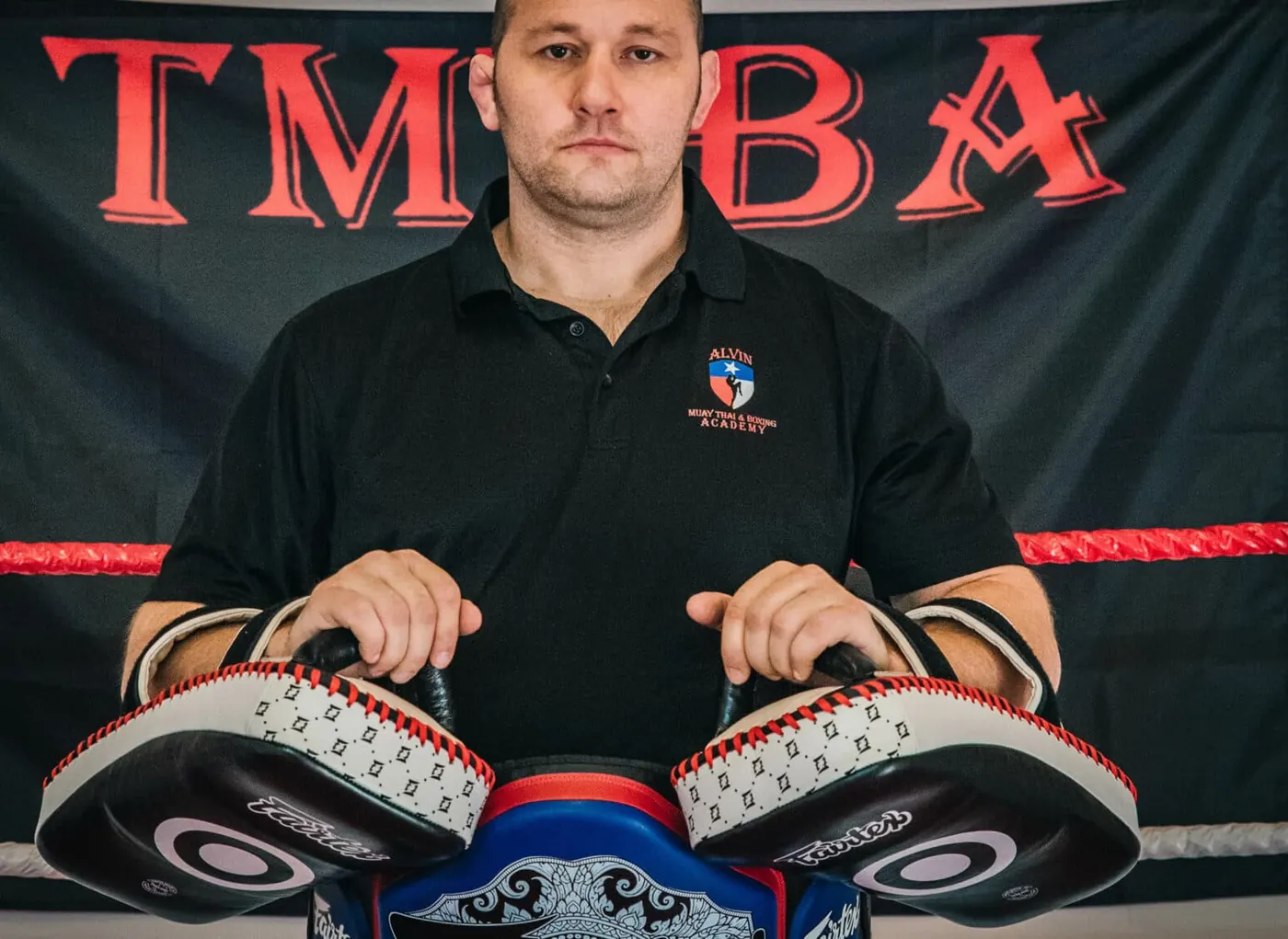 Kru Jonathan Harris holding Thai pads in the ring