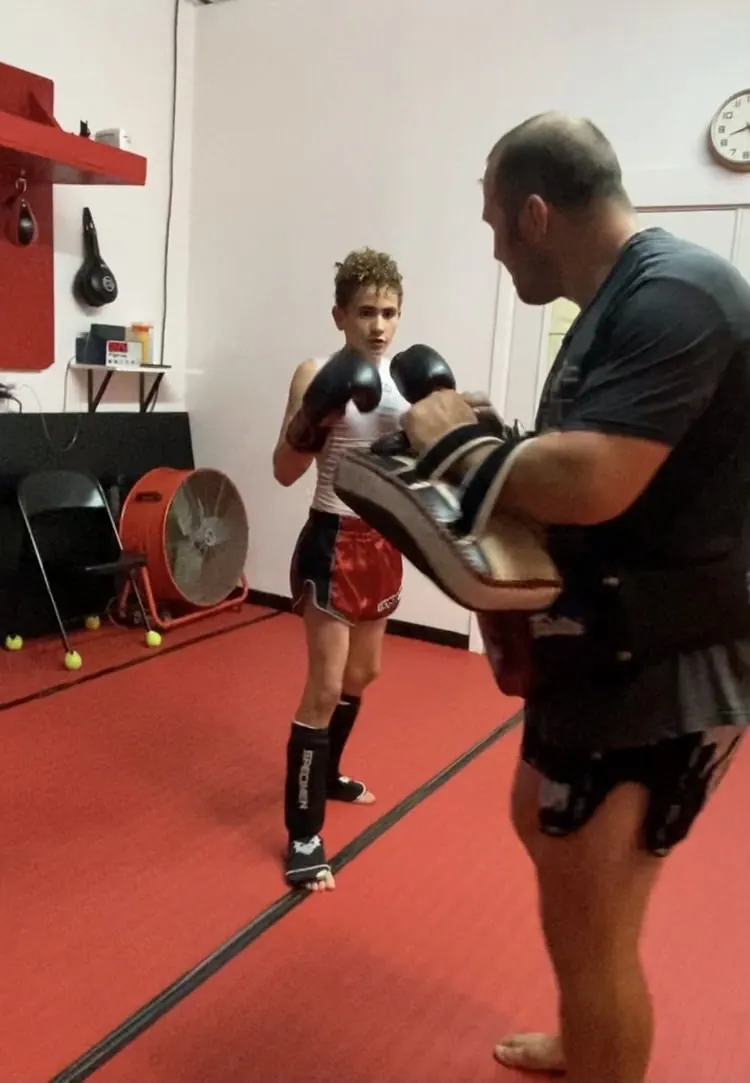 Kru Jonathan holding pads for a young student
